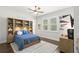 Stylish bedroom with a custom built-in bookcase, bed, and natural light, creating a tranquil space at 16119 Carencia Ln, Odessa, FL 33556
