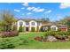 Stately two-story home with a tile roof, manicured lawn, and beautiful landscaping and flower beds at 16119 Carencia Ln, Odessa, FL 33556