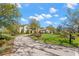 Inviting front yard with a circular driveway, lush lawn, and mature trees creating a picturesque setting for this exquisite home at 16119 Carencia Ln, Odessa, FL 33556