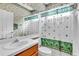 Bright bathroom featuring seashell motif shower curtain, white tile, and wood vanity at 19106 Abercorn Pl, Lutz, FL 33558