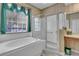 Bright bathroom featuring a soaking tub, walk-in shower, decorative wallpaper, and a large window at 19106 Abercorn Pl, Lutz, FL 33558