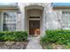 Inviting entryway featuring double doors, sidelights, decorative wreaths, and lush green landscaping at 19106 Abercorn Pl, Lutz, FL 33558