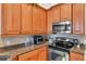 Well-lit kitchen features stainless steel microwave and oven, with wood cabinets and granite countertops at 19106 Abercorn Pl, Lutz, FL 33558