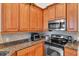Well-lit kitchen features stainless steel microwave and oven, with wood cabinets and granite countertops at 19106 Abercorn Pl, Lutz, FL 33558