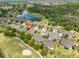 Aerial view of a home with beautiful landscaping, a two car garage and views of a golf course and pond at 1916 Inverness Greens Dr, Sun City Center, FL 33573