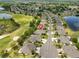 Aerial view of a home with beautiful landscaping, a two car garage and views of a golf course and pond at 1916 Inverness Greens Dr, Sun City Center, FL 33573