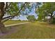 Picturesque backyard with mature shade trees, lush lawn, and scenic walking path at 1916 Inverness Greens Dr, Sun City Center, FL 33573