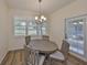 Cozy dining room with wood floors, wood table, chairs, chandelier, and a sunlit window at 1916 Inverness Greens Dr, Sun City Center, FL 33573