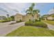 Charming front exterior with a well-manicured lawn, a two car garage, and lush landscaping at 1916 Inverness Greens Dr, Sun City Center, FL 33573