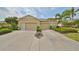 Charming front exterior with a well-manicured lawn, a two car garage, and lush landscaping at 1916 Inverness Greens Dr, Sun City Center, FL 33573