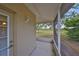 A screened porch with an outdoor light fixture, view of a green lawn, and a pathway beyond at 1916 Inverness Greens Dr, Sun City Center, FL 33573