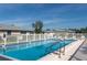 Sparkling community pool area featuring a metal ladder, a white fence, and plenty of lounge chairs at 2182 Corinne S Ct # C, St Petersburg, FL 33712