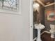 Stylish powder room boasts pedestal sink, stained-glass window, and elegant fixtures in neutral tones at 2807 N Morgan St, Tampa, FL 33602