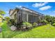 A tranquil view of the home's screened lanai, lush landscaping and backyard at 30900 Spruceberry Ct, Wesley Chapel, FL 33543