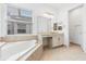 Bright bathroom featuring a soaking tub, vanity with double sinks, and tiled floors at 30900 Spruceberry Ct, Wesley Chapel, FL 33543