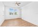 White bedroom with wood-look floors, ceiling fan, and two windows at 30900 Spruceberry Ct, Wesley Chapel, FL 33543