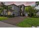 A home boasting a triple garage, stone accents, and lush landscaping, with a brick-paved driveway at 30900 Spruceberry Ct, Wesley Chapel, FL 33543