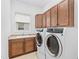 Bright laundry room featuring sink, wooden cabinets, and modern washer and dryer at 30900 Spruceberry Ct, Wesley Chapel, FL 33543