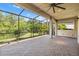 Covered brick patio with screened enclosure offering views of the landscaped yard at 30900 Spruceberry Ct, Wesley Chapel, FL 33543