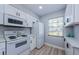 Bright kitchen featuring white cabinets, modern appliances and wood look flooring at 3143 Mission Grove Dr, Palm Harbor, FL 34684