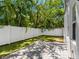 Backyard featuring a white fence, grass, and paver patio shaded by leafy trees at 410 S Church Ave, Tampa, FL 33609
