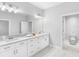 Bright bathroom featuring double sinks, white cabinets, and marble countertops at 410 S Church Ave, Tampa, FL 33609