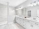 This luxurious bathroom is complete with a double vanity, a walk-in shower, and white marble-style tiling at 410 S Church Ave, Tampa, FL 33609