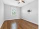 Well-lit bedroom with hardwood floors, ceiling fan, and a wall-mounted television bracket at 410 S Church Ave, Tampa, FL 33609