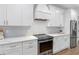 Modern kitchen featuring white cabinets, gray backsplash, stainless steel appliances, and range hood at 410 S Church Ave, Tampa, FL 33609