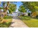 Lovely home surrounded by mature trees and a lush green lawn with a paved driveway at 5809 Dartmouth N Ave, St Petersburg, FL 33710