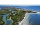 Beautiful aerial view of the waterfront property and surrounding coastal landscape featuring a sandy beach and lush greenery at 706 Bunker View Dr, Apollo Beach, FL 33572