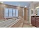Bathroom with soaking tub, walk-in shower, white plantation shutters and stone-look porcelain tiling at 706 Bunker View Dr, Apollo Beach, FL 33572