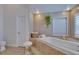Bathroom with soaking tub, white plantation shutters, and decorative tiling at 706 Bunker View Dr, Apollo Beach, FL 33572