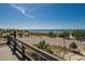 Scenic view of a sandy beach, clear ocean, and a pier with a covered gazebo from an elevated wooden deck at 706 Bunker View Dr, Apollo Beach, FL 33572