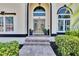 Inviting front entrance with double doors, steps, and a paved walkway, enhanced by neatly trimmed shrubs and potted plants at 706 Bunker View Dr, Apollo Beach, FL 33572