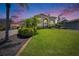 Beautiful home with lush green lawn and mature tropical landscaping under a beautiful sunset at 706 Bunker View Dr, Apollo Beach, FL 33572