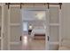 Main bedroom showcasing wood floors, chandelier, and stylish sliding barn doors at 706 Bunker View Dr, Apollo Beach, FL 33572
