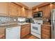 Well-lit kitchen features white appliances, light wood cabinets, and decorative backsplash at 13225 101St St # 107, Largo, FL 33773