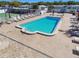 An aerial captures a refreshing community pool with deck chairs, set amidst palm trees and sunny skies at 13225 101St St # 107, Largo, FL 33773