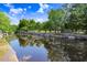 Scenic waterfront view along a calm canal, reflecting the surrounding lush greenery under a bright, cloudy sky at 14612 Coral Dr, Hudson, FL 34667