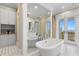 Bathroom featuring white soaking tub, a decorative mirror, and french doors leading to a balcony with ocean views at 1695 Brightwaters Ne Blvd, St Petersburg, FL 33704