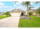 Inviting single-Gathering house featuring a well-maintained lawn, palms, and a spacious two-car garage at 18150 Leamington Ln, Land O Lakes, FL 34638