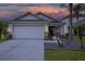 Inviting single-Gathering house featuring a well-maintained lawn, palms, and a spacious two-car garage at 18150 Leamington Ln, Land O Lakes, FL 34638