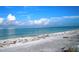 Serene beachfront with clear turquoise water under a bright blue sky with scattered white clouds at 204 Shore W Dr, Oldsmar, FL 34677