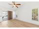 Bright bedroom with hardwood floors featuring a ceiling fan and a view to the home exterior through the windows at 2449 Running Oak Ct, Spring Hill, FL 34608