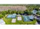 An aerial view of tennis courts, pickleball courts, sand volleyball and pool surrounded by trees at 28402 Openfield Loop, Wesley Chapel, FL 33543