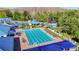Aerial view of the community pool featuring lap lanes, a splash pad, sun loungers, and shade structures surrounded by trees at 28402 Openfield Loop, Wesley Chapel, FL 33543