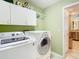 Modern laundry room featuring washer, dryer, overhead cabinets, and access to the kitchen at 28402 Openfield Loop, Wesley Chapel, FL 33543
