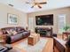 Comfortable living room with a large brown leather sofa, wooden floors, ceiling fan, and entertainment center at 28402 Openfield Loop, Wesley Chapel, FL 33543