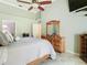Bright primary bedroom featuring a vaulted ceiling, tile floor, and a dresser with a mirror at 28402 Openfield Loop, Wesley Chapel, FL 33543